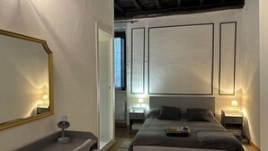 Une chambre moderne avec un grand lit, des tables de chevet avec des lampes, un bureau avec une chaise et un miroir.