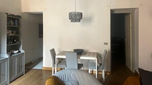 Un coin repas comprenant une table et des chaises, un luminaire suspendu et un meuble contenant de la vaisselle.