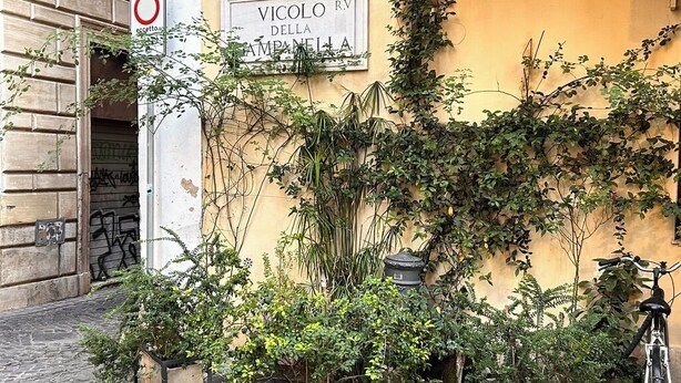 Un bâtiment avec une enseigne indiquant « VICOLO RV DELLA CAMPANELLA » et un panneau interdisant le stationnement. On y voit des plantes en pot et un vélo devant l’entrée.