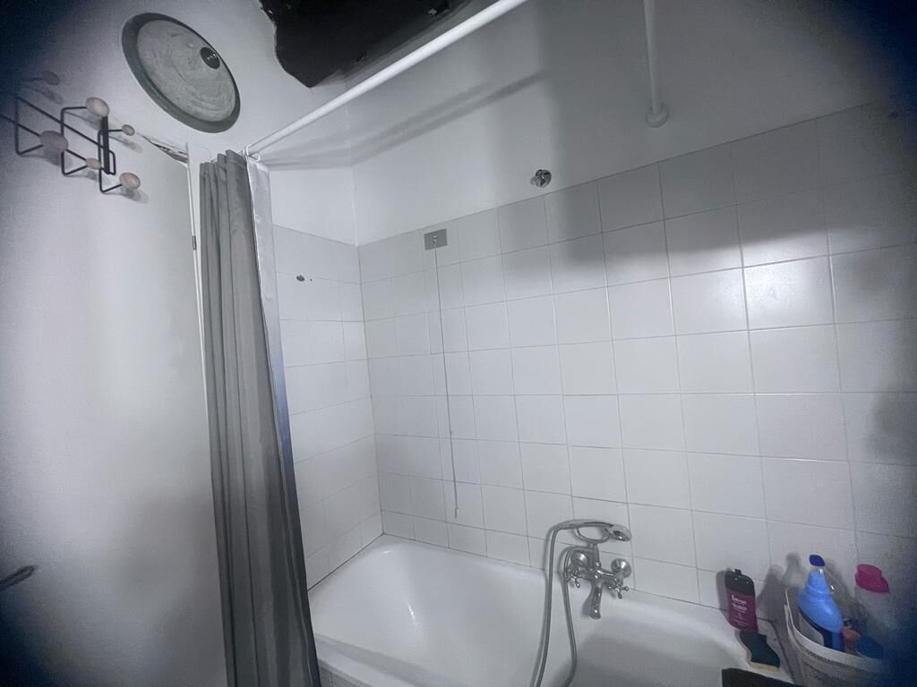 A bathroom with a bathtub, a shower, and a toilet. There are toiletries on the floor.