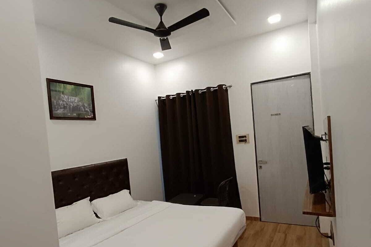 A bedroom with a bed, a ceiling fan, a door, and a small table.