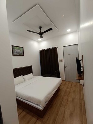 Un dormitorio con cama, ventilador de techo, una puerta y una mesita.