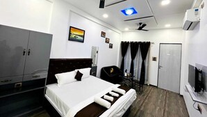 Une chambre d’hôtel équipée d’un lit, d’un bureau, d’une armoire, d’un ventilateur de plafond et d’une télévision.