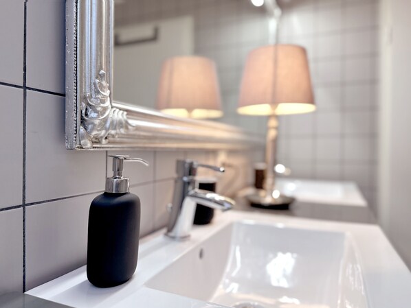 Une salle de bain avec un lavabo blanc, un miroir et un distributeur de savon.