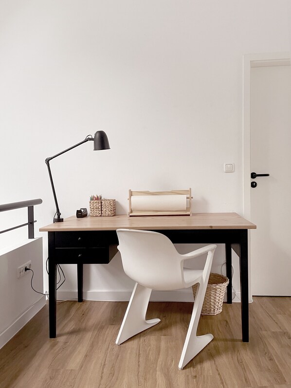 A minimalist office setup with a desk, chair, lamp, and a door. - Ferienhaus Strand und Wald - Für Familien & Freunde, Ruhige, Zentrale Lage (Zinnowitz)
