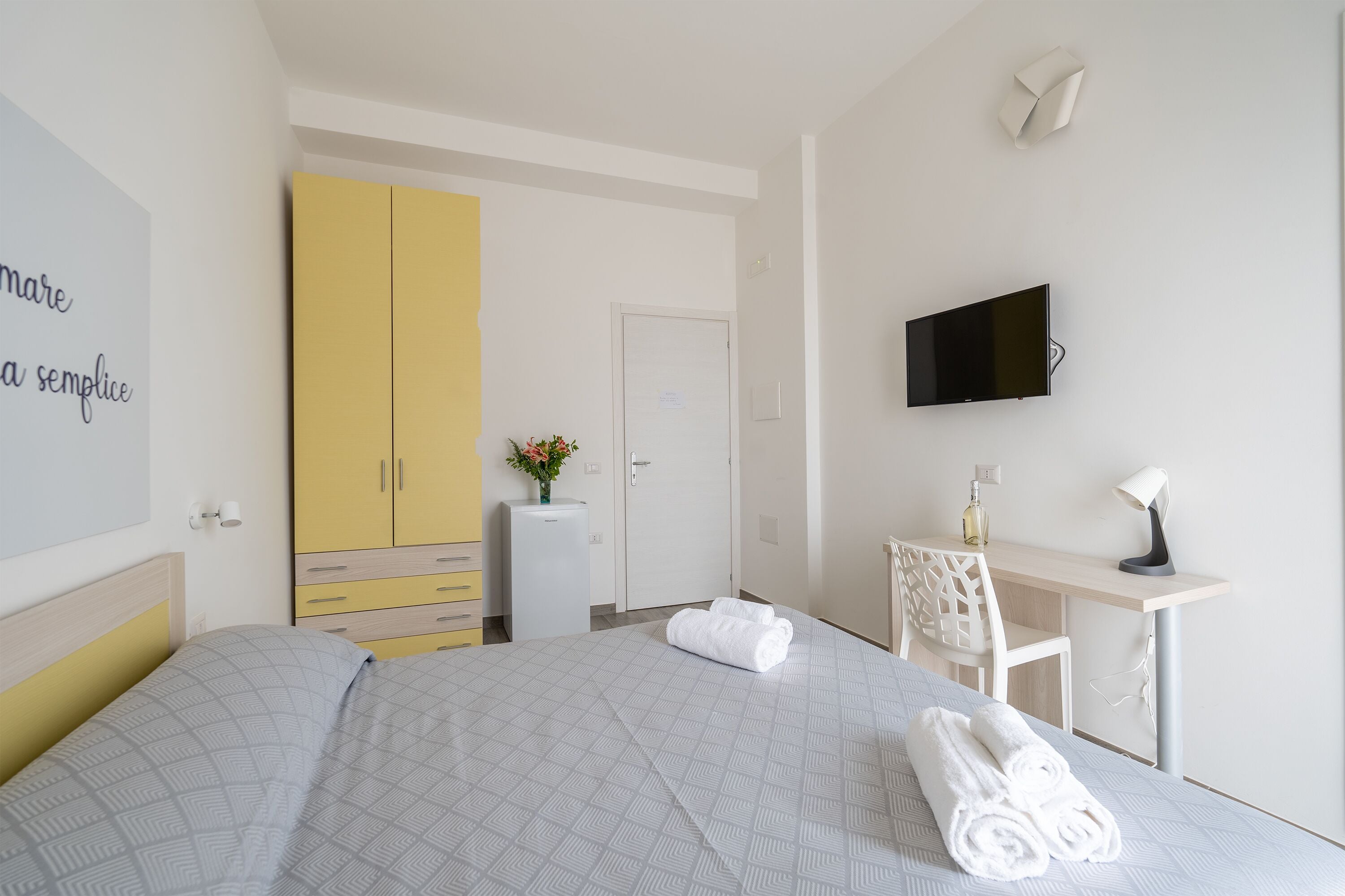 A hotel room with a bed, a desk, a TV, and a wardrobe.