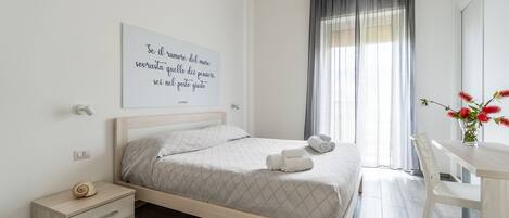 A neatly arranged bedroom with a bed, bedside table, and a wall-mounted air conditioner.