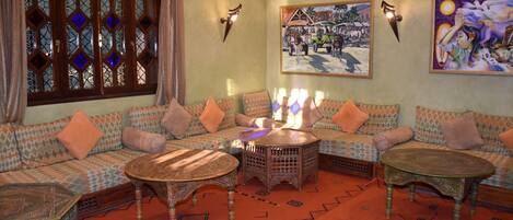 A traditional Moroccan-style living room with patterned sofas, a central coffee table, and decorative wall art.