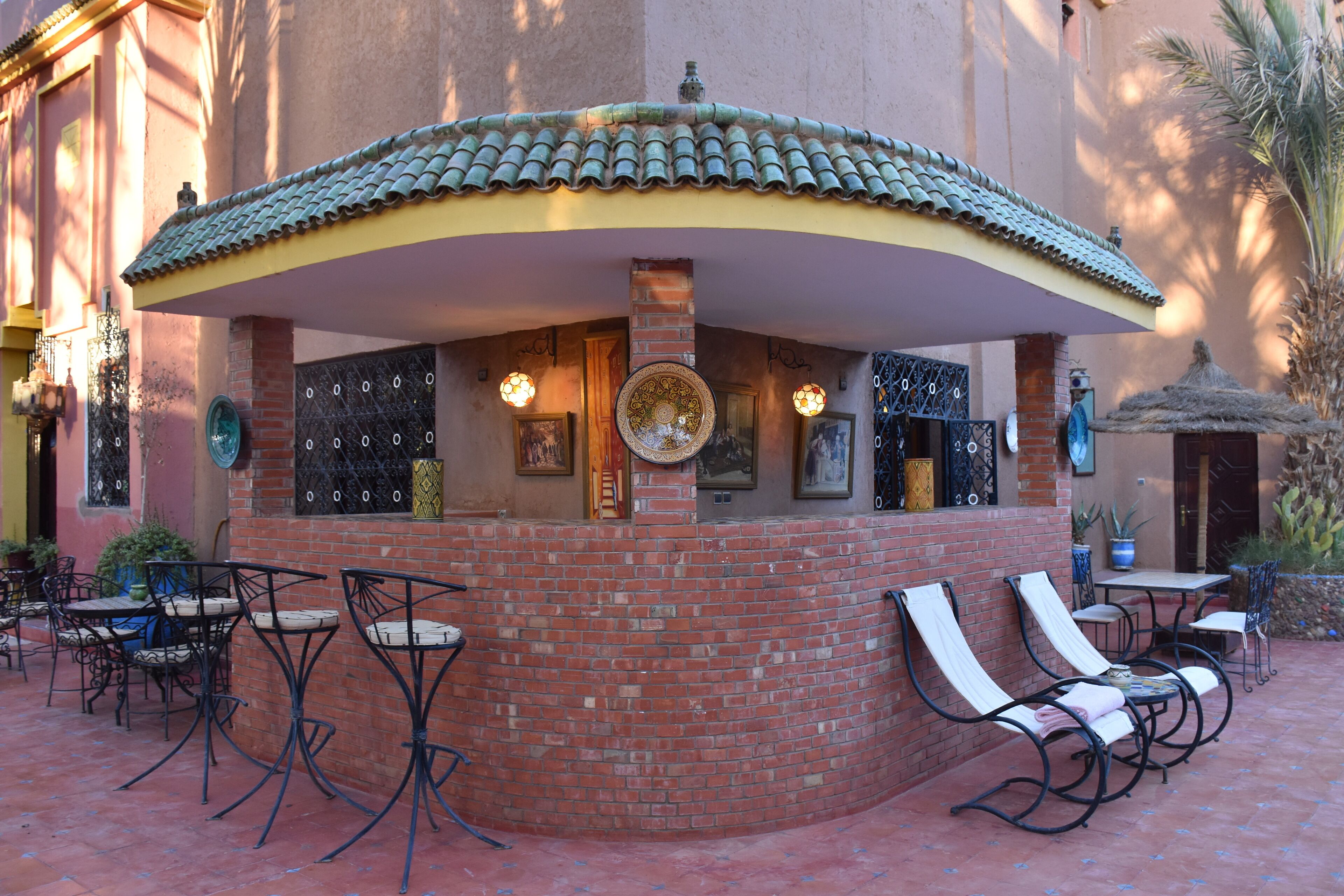 A brick outdoor seating area with tables and chairs, a decorative arch, and a small fountain.