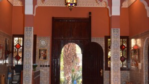 A traditional interior with a fountain, patterned walls, and a large wooden door. - Riad le Petit Jardin  (Zagora)