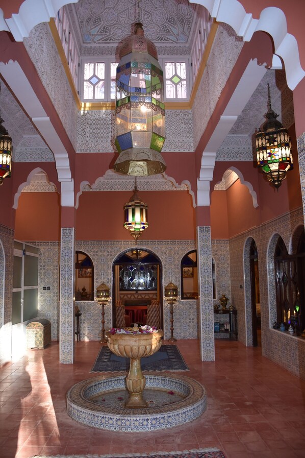 A spacious lobby with intricate tile work, a central fountain, and ornate lighting fixtures.