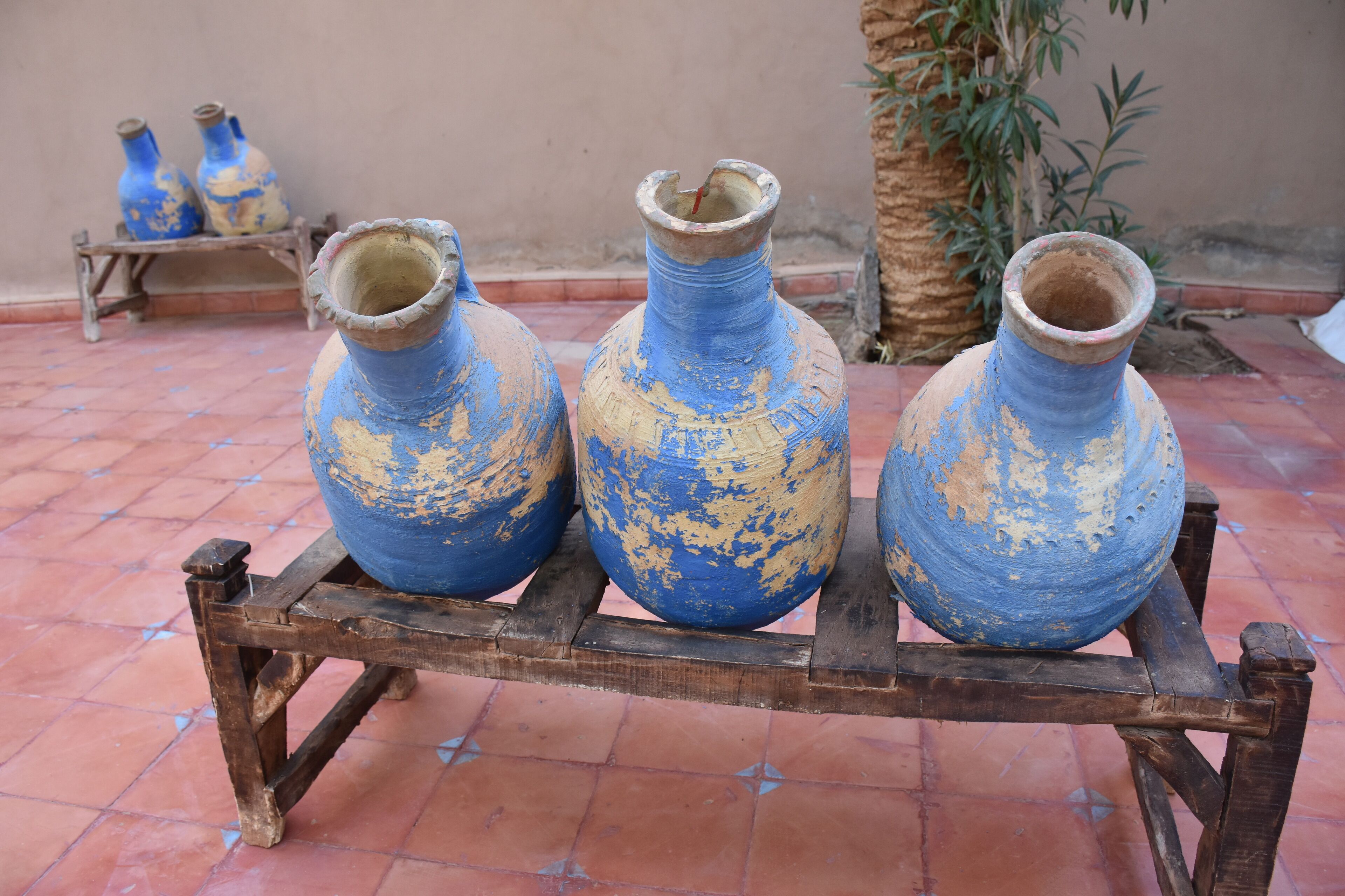 Trois vases bleus posés sur un présentoir en bois.