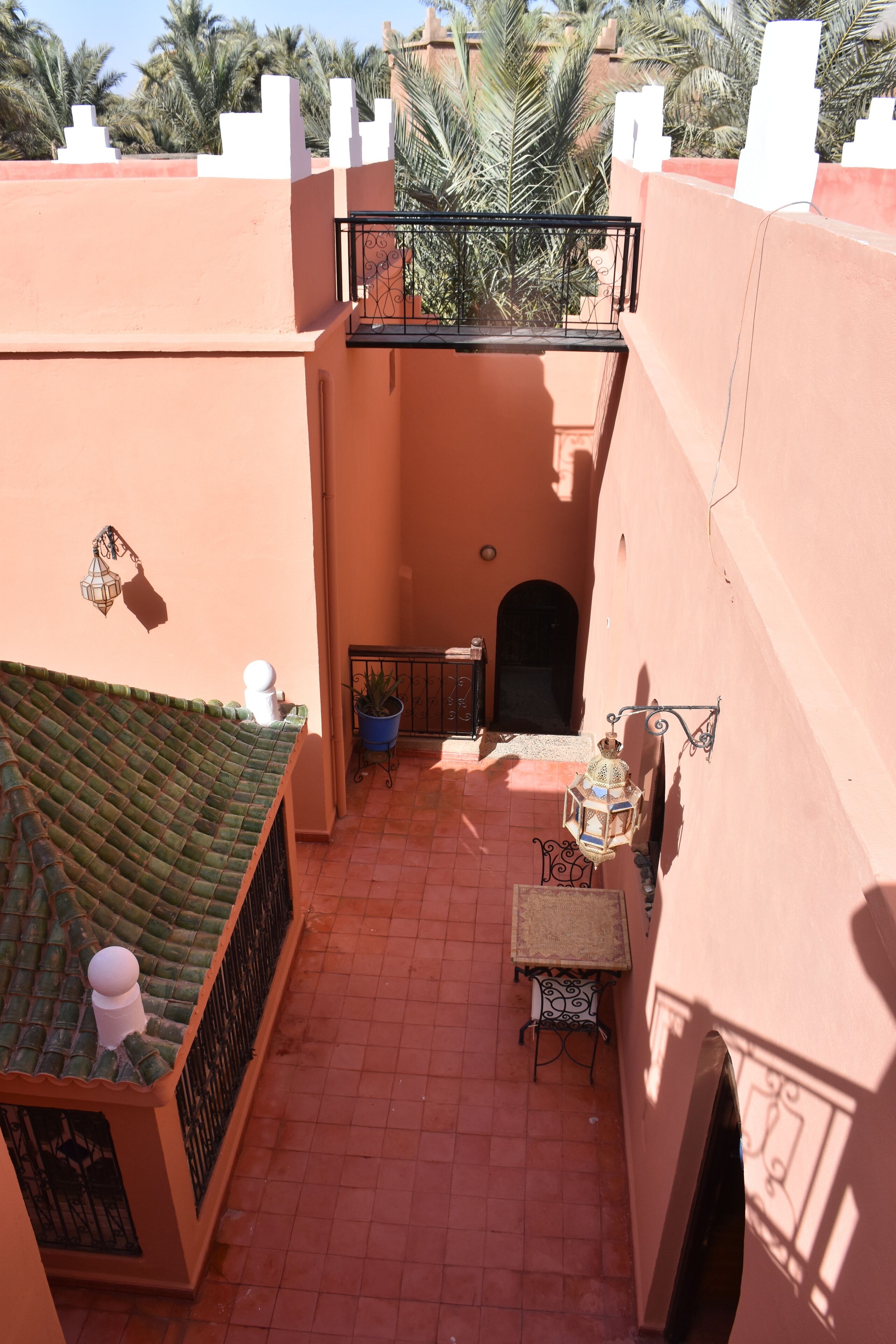 A courtyard with a tiled floor, a small table with chairs, a potted plant, and a decorative lantern.