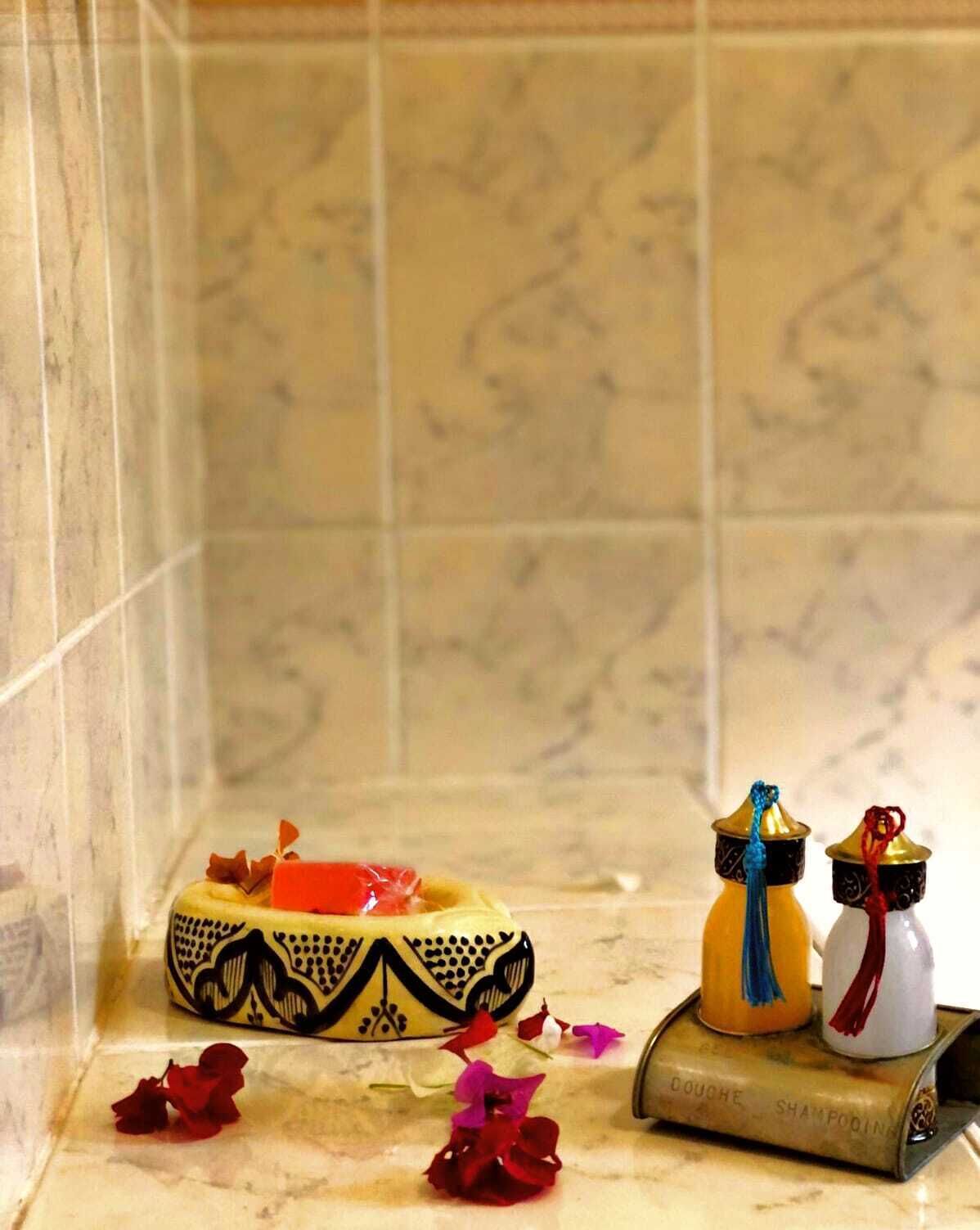 A bathroom with a marble floor, a decorative soap dish, and a shampoo bottle.