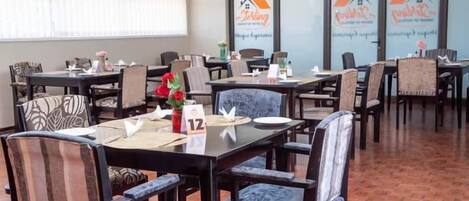 A dining area with tables and chairs, some with floral centerpieces.