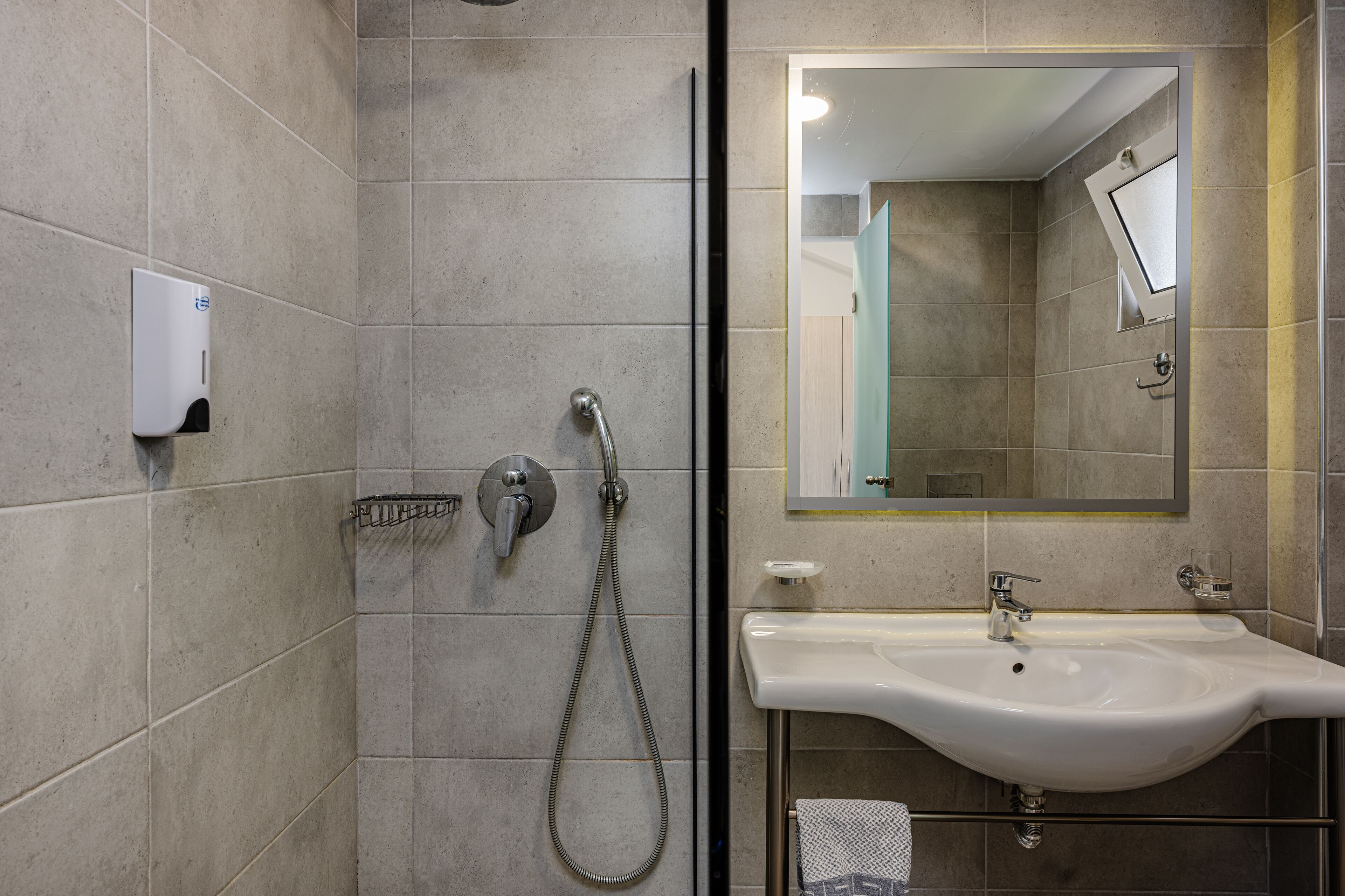 A bathroom with a shower, a sink, and a mirror.