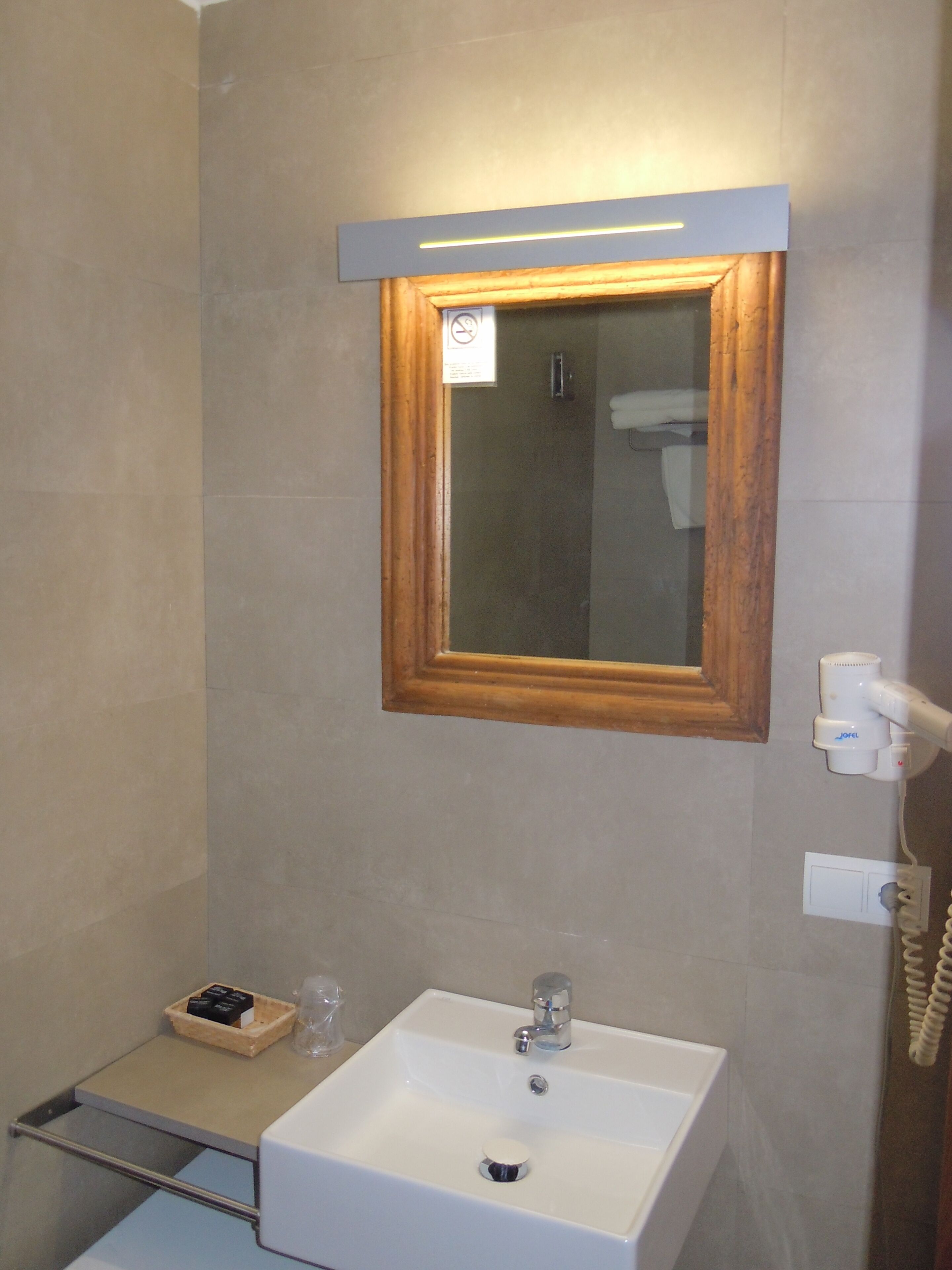 A bathroom with a white sink, a mirror with a wooden frame, and a towel rack.