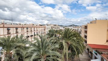 Vista de un edificio con varios pisos, balcones y palmeras al frente.