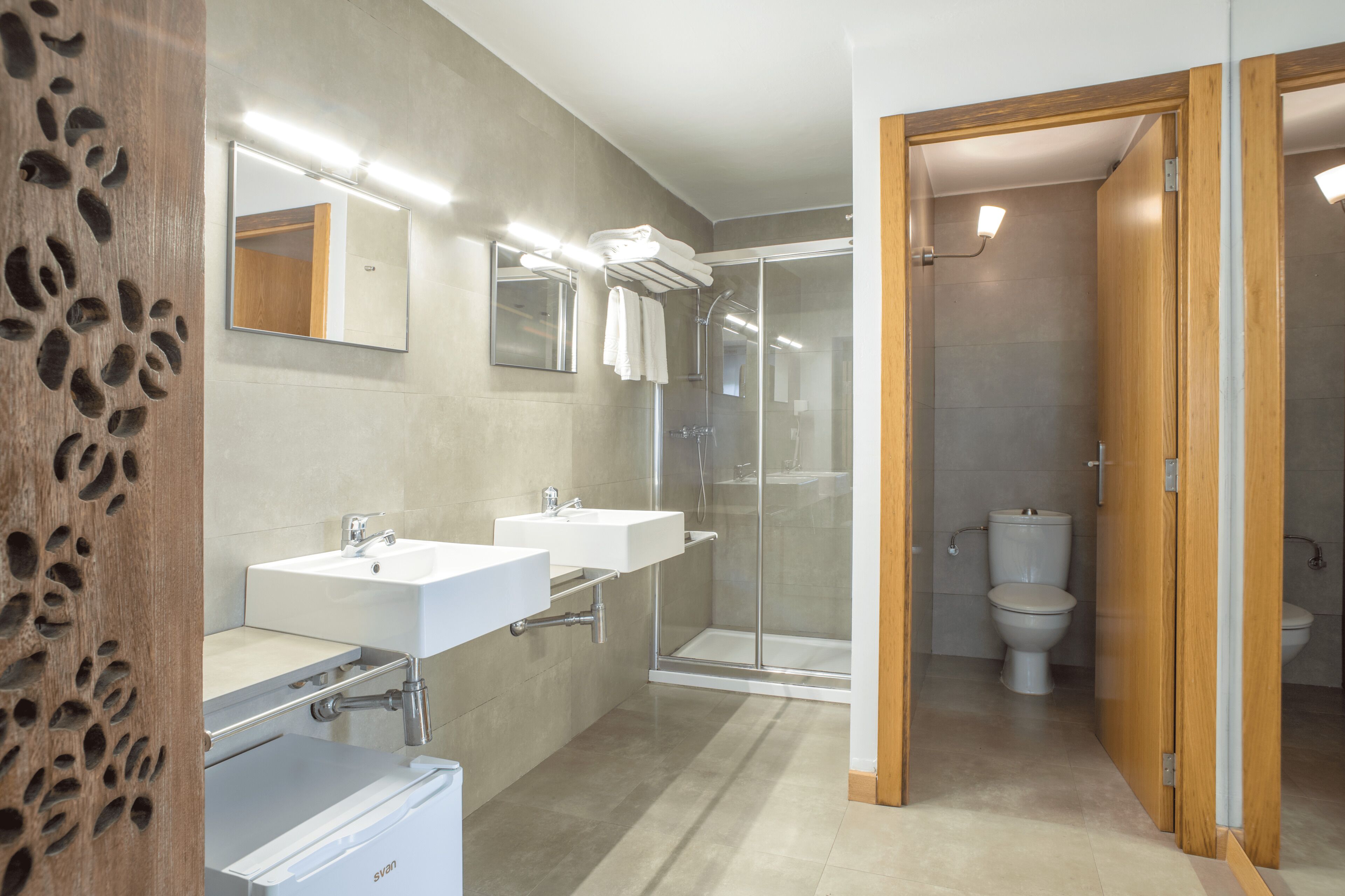 Une salle de bain moderne avec deux lavabos, une douche à l’italienne et des toilettes.