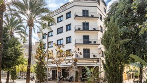 A multi-story building with balconies, outdoor seating, and palm trees.
