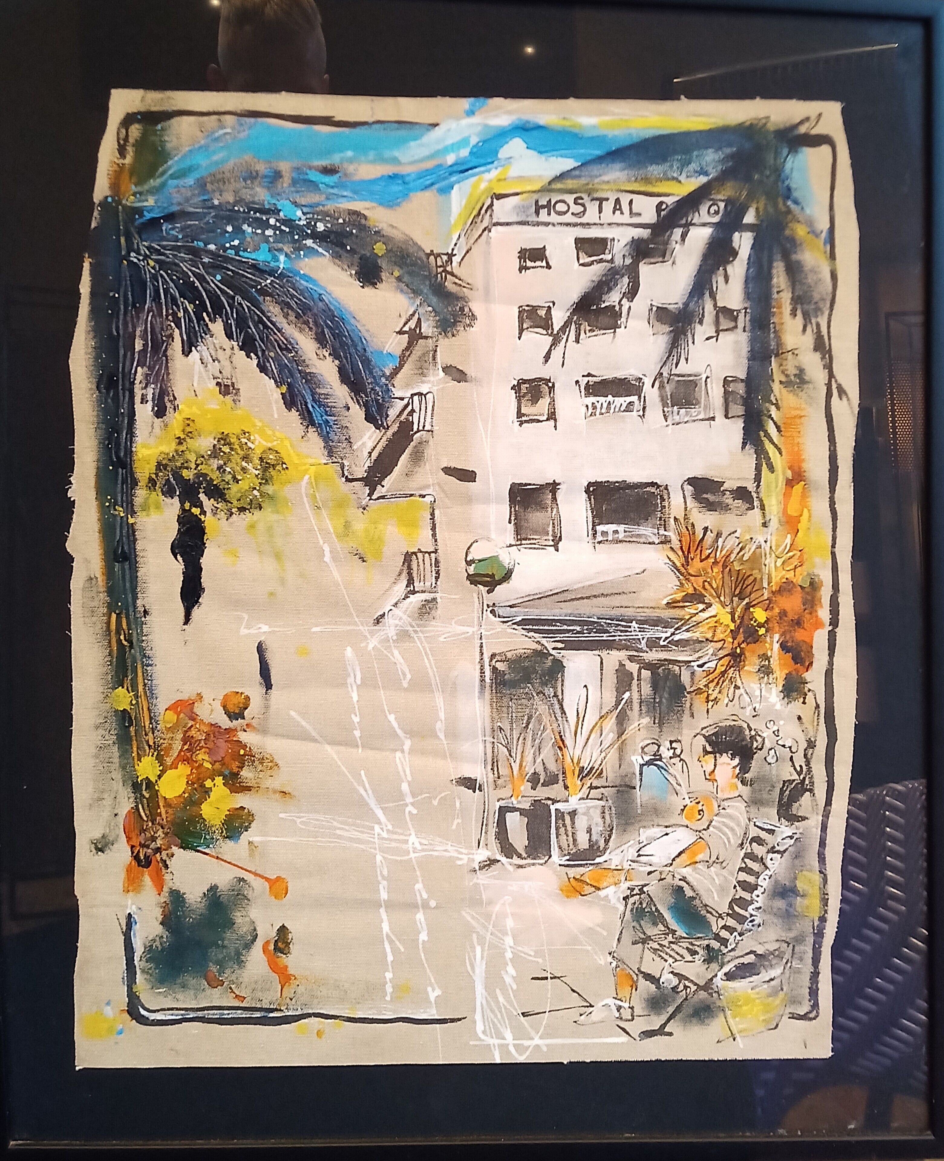 Un dessin représentant un bâtiment sur lequel est inscrit le mot « HOSTAL », avec un balcon, une table entourée de chaises et une personne assise.