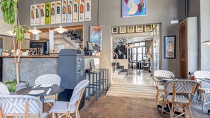 A restaurant with wicker chairs, a counter with a coffee machine, and artwork on the walls.