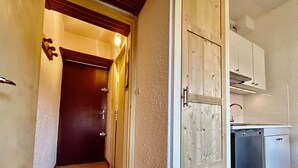 A narrow hallway with a wooden door leading to a kitchen area. - Cozy studio 3 pers, near lifts and parking (La Salle-les-Alpes)
