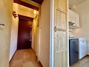A narrow hallway with a wooden door leading to a kitchen area. - Cozy studio 3 pers, near lifts and parking (La Salle-les-Alpes)
