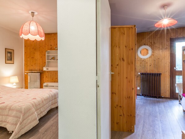A bedroom with a bed, a wooden wardrobe, a radiator, and a ceiling light fixture.