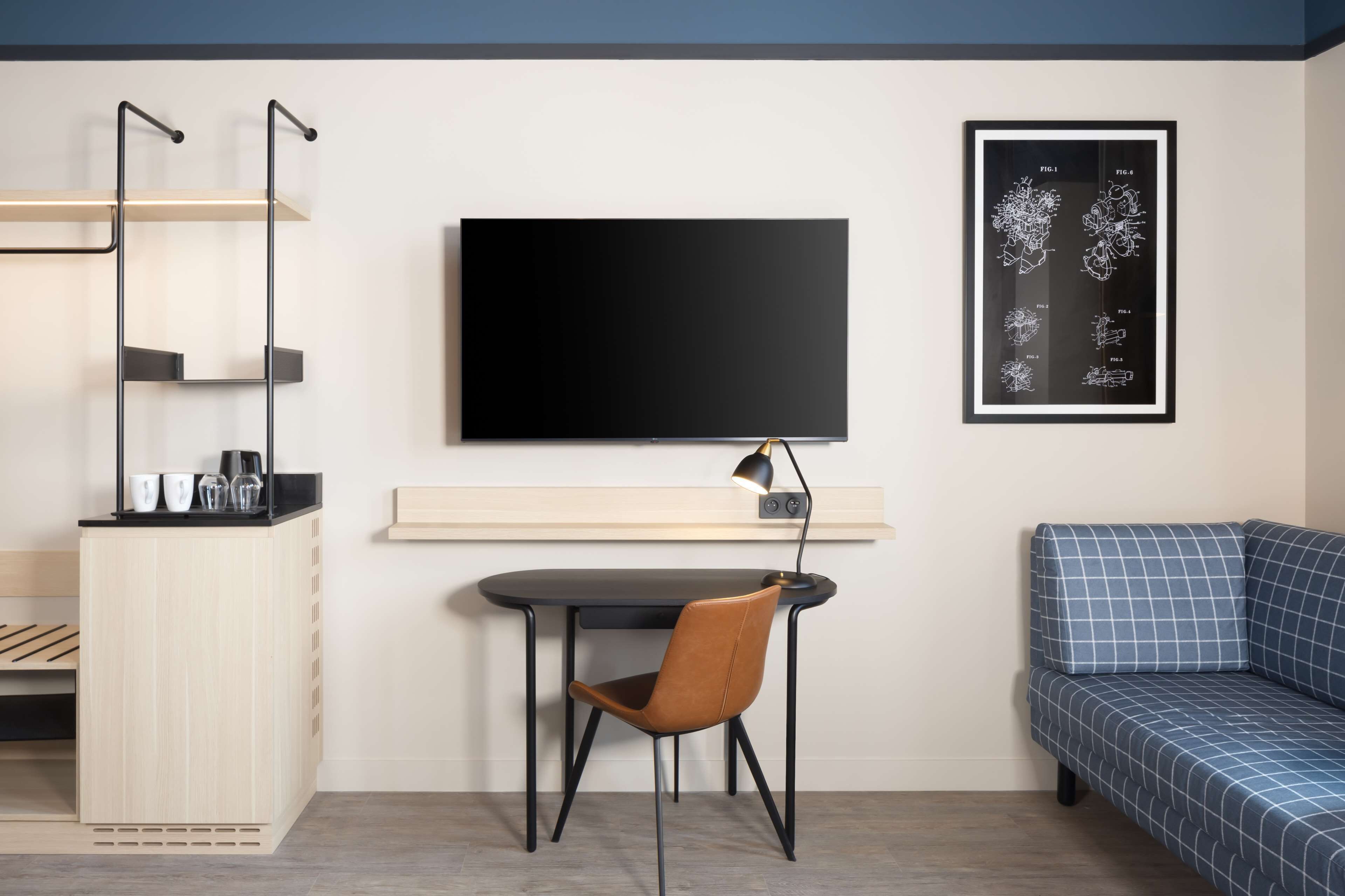 Une chambre moderne équipée d’un bureau, d’une chaise et d’un canapé bleu.