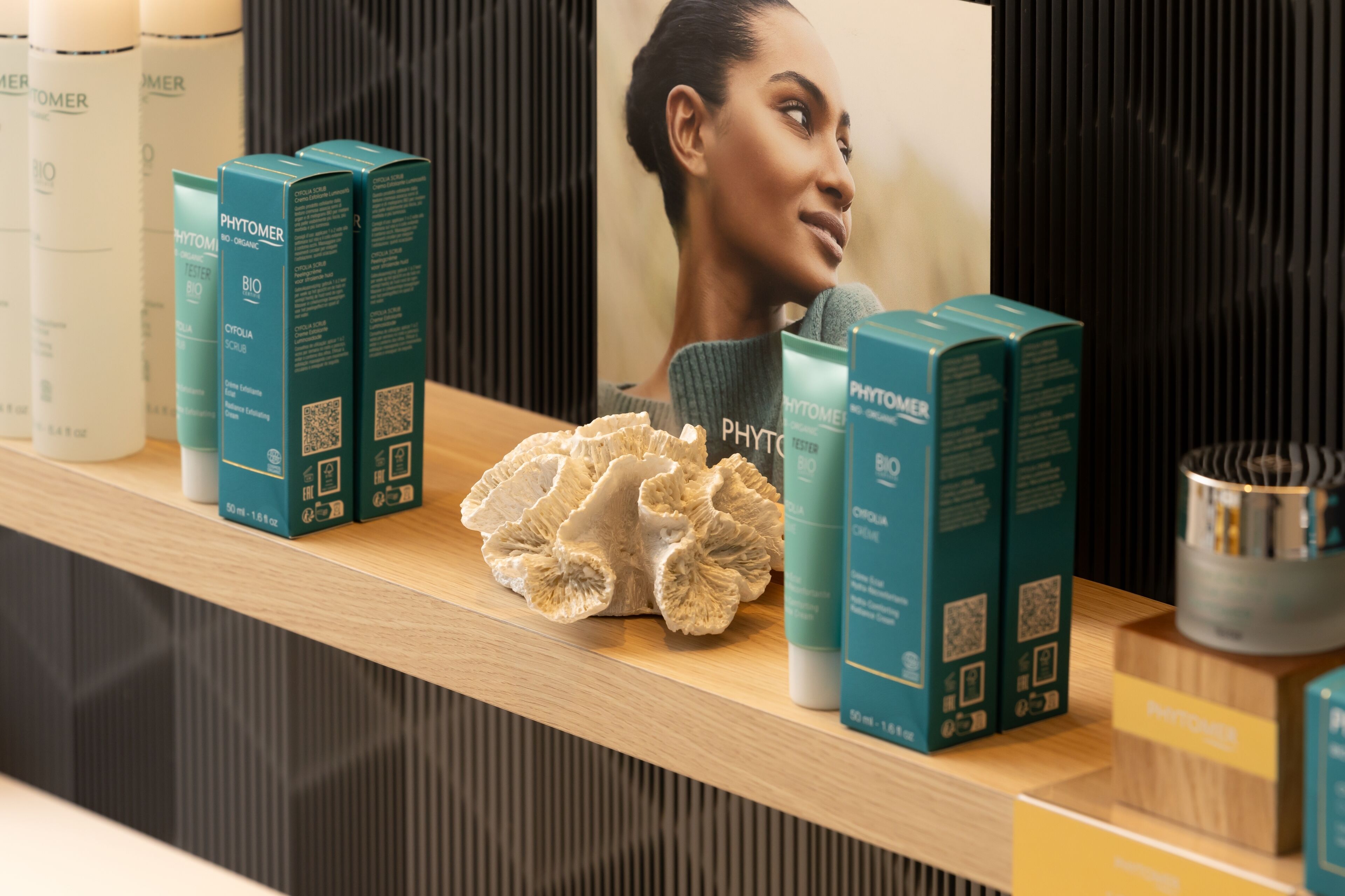 Una estantería con varios productos para el cuidado de la piel y un trozo de coral.