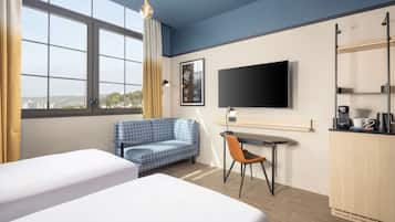 A hotel room with two beds, a desk with a chair, a TV, and a city view.