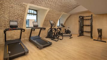 Une salle de sport équipée de tapis de course, de vélos elliptiques et d'un espace dédié à la musculation.