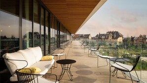 A modern outdoor terrace with a wooden ceiling, glass walls, and a view of residential buildings. - Hyatt Place Rouen (Rouen)