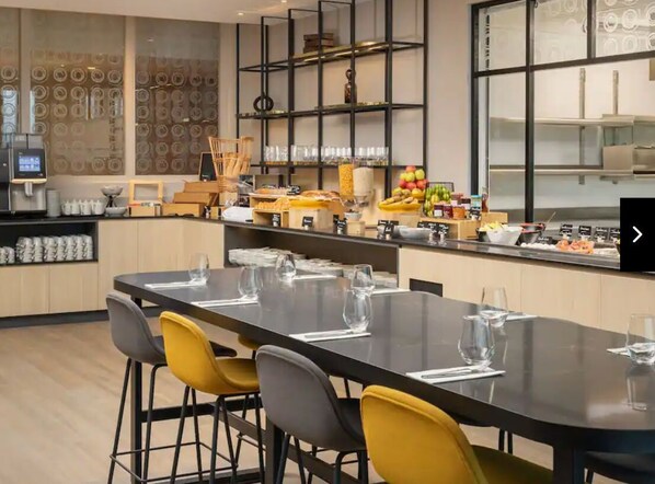 A modern dining area with a long table set for six, surrounded by yellow chairs. - Hyatt Place Rouen (Rouen)