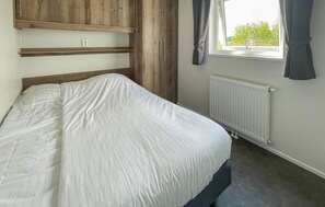 Cozy retreat with a single bed, wardrobe, and window with curtains.