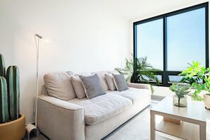 A modern living room with a sofa, pillows, a coffee table, and potted plants.