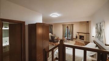 A spacious bedroom with a large wardrobe, a cozy seating area with a fireplace, and a balcony with curtains.