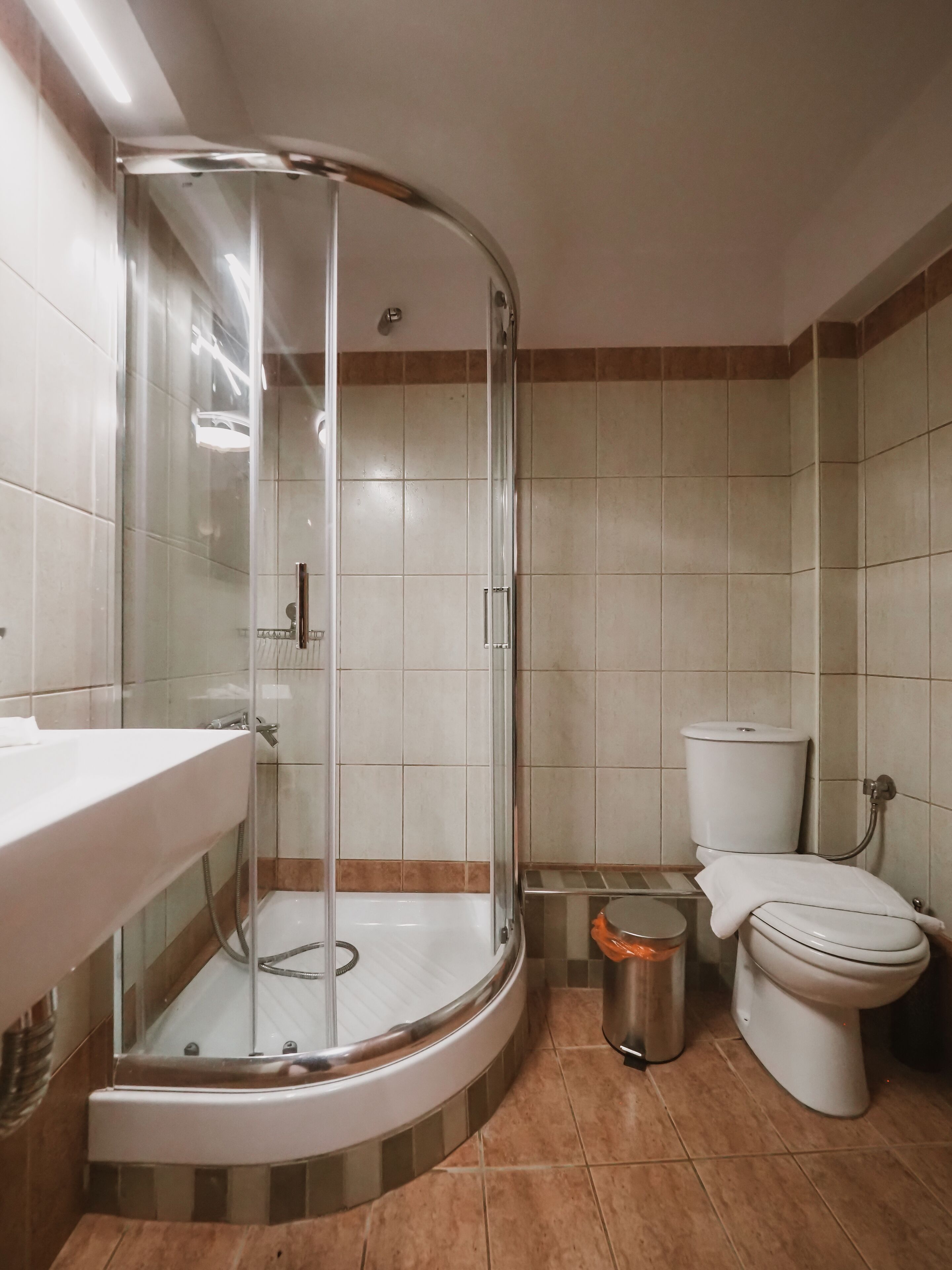 A bathroom with a glass-enclosed shower, a toilet, and a sink.