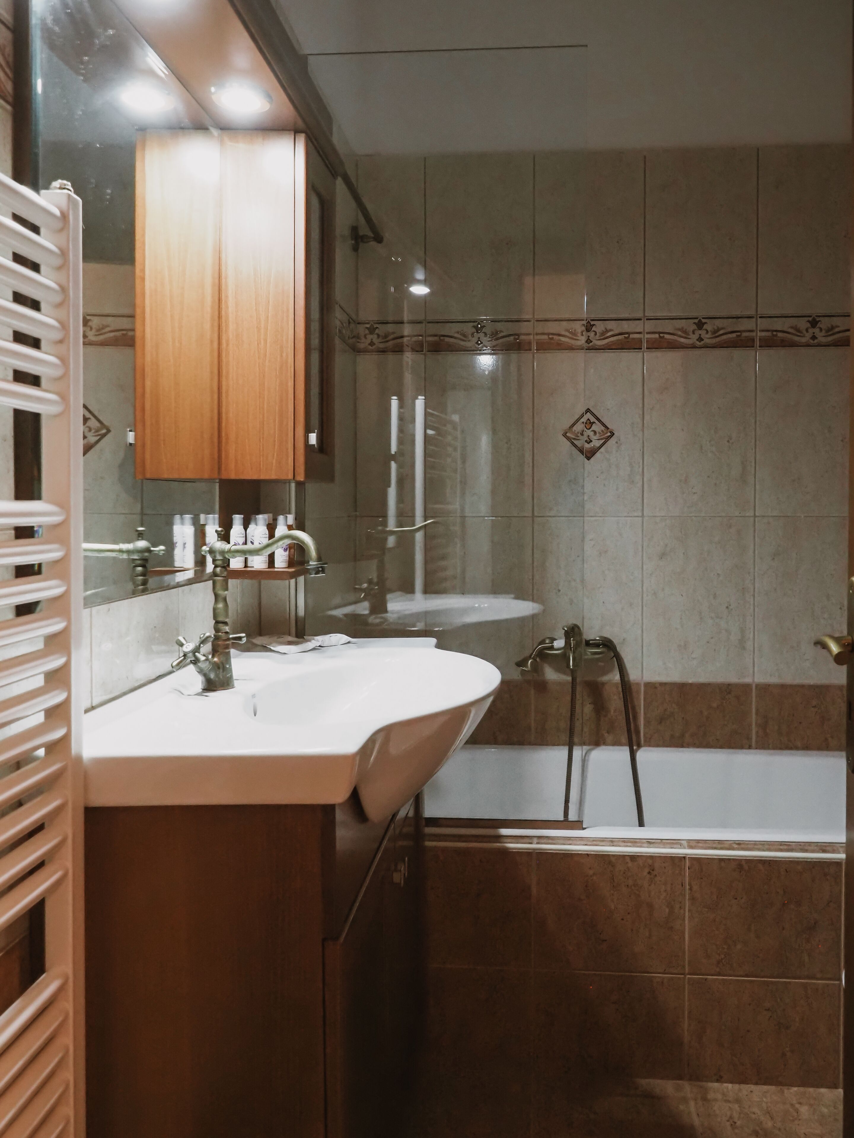 Une salle de bain avec un meuble-lavabo en bois, deux vasques, une baignoire et une douche.