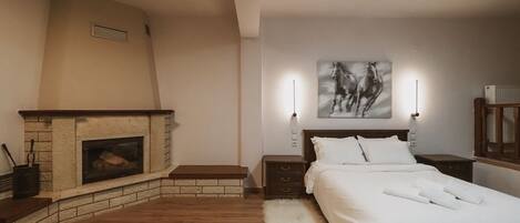 A bedroom with a fireplace, a bed with white bedding, a fluffy rug, and a painting of horses on the wall.