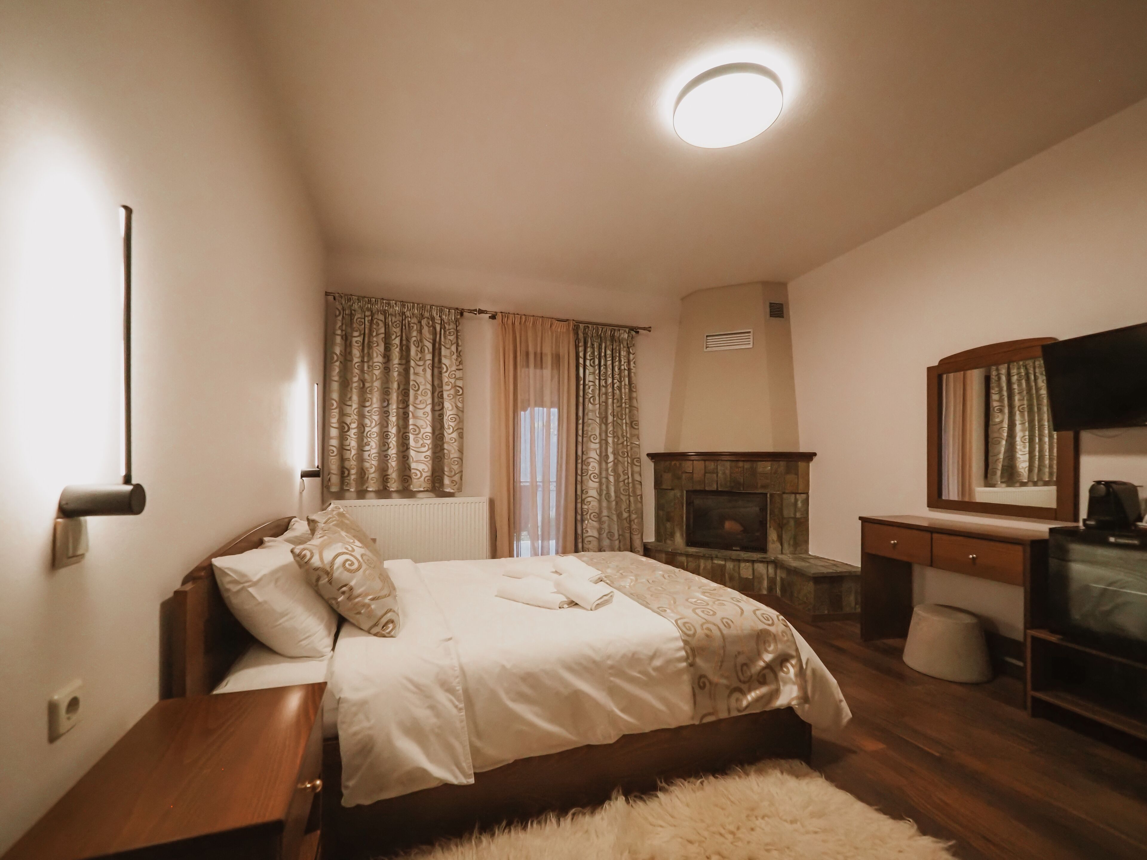 Una camera da letto con un letto, un camino, una televisione e uno specchio.