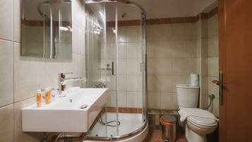 Ett modernt badrum med en duschavdelning med glasväggar, en vit tvättställskommod med plats för toalettartiklar och en toalett.