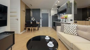 Un salon moderne avec une table basse noire, un canapé beige et un téléviseur posé sur un meuble noir.