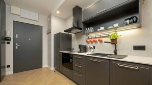 Une cuisine moderne avec des meubles de rangement sombres, un four encastré, un évier et un plan de travail.