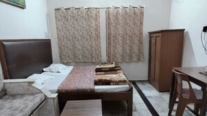 A bedroom with a bed, a wooden bench, a desk, and a wardrobe. - Hotel Rawat (Jodhpur)