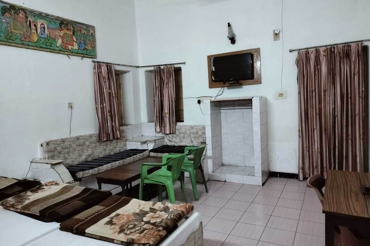 A room with a sofa, a television mounted on the wall, a fireplace, and curtains.
