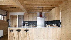 Una cocina moderna con armarios de madera, un refrigerador de acero inoxidable y una isla central con taburetes.