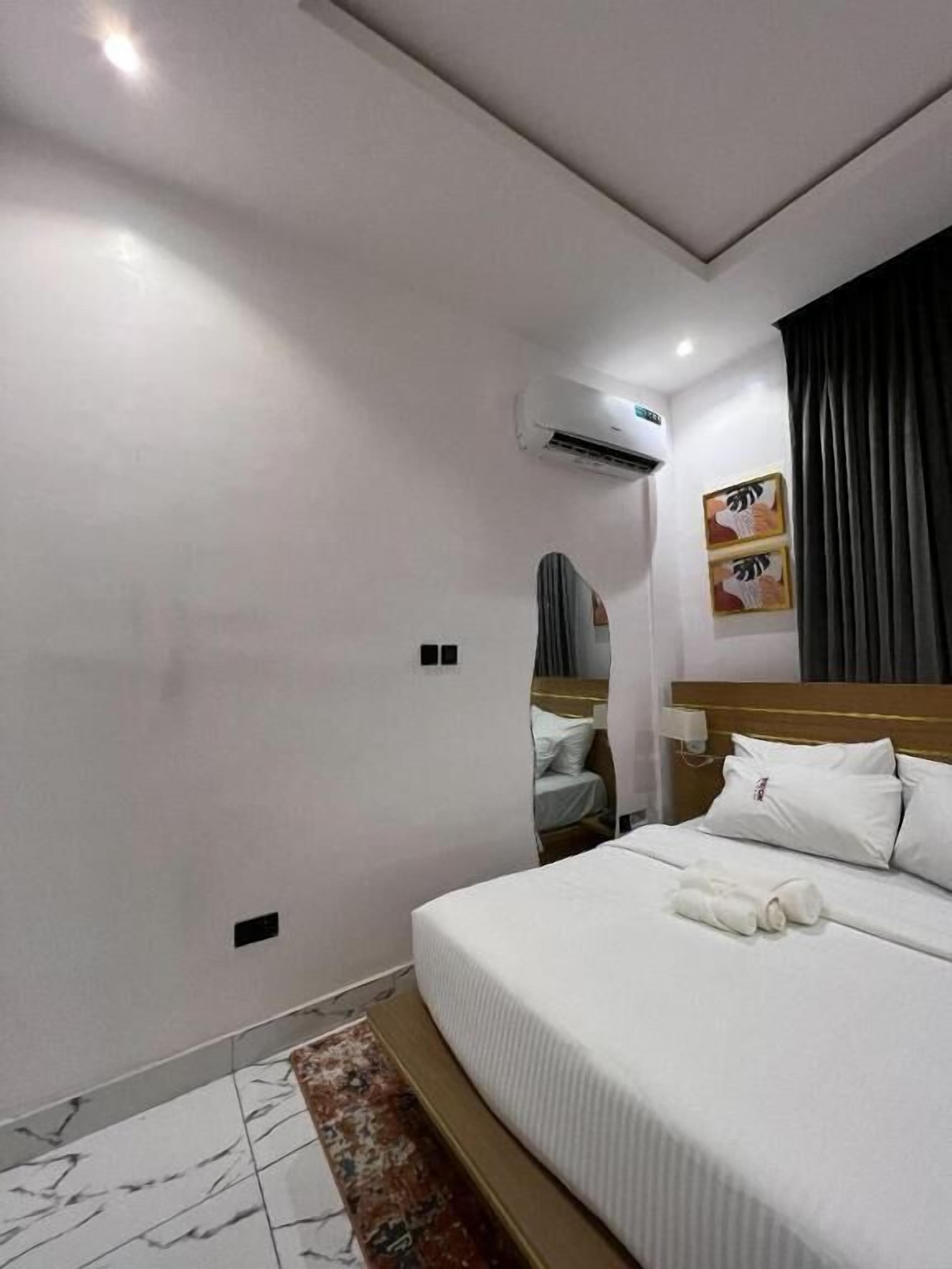A hotel room with a bed, a small table, and an air conditioning unit on the wall.