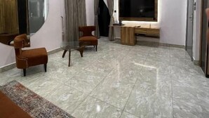 Un salon moderne doté d’un grand téléviseur à écran plat, d’une table basse en verre et de deux fauteuils marron.